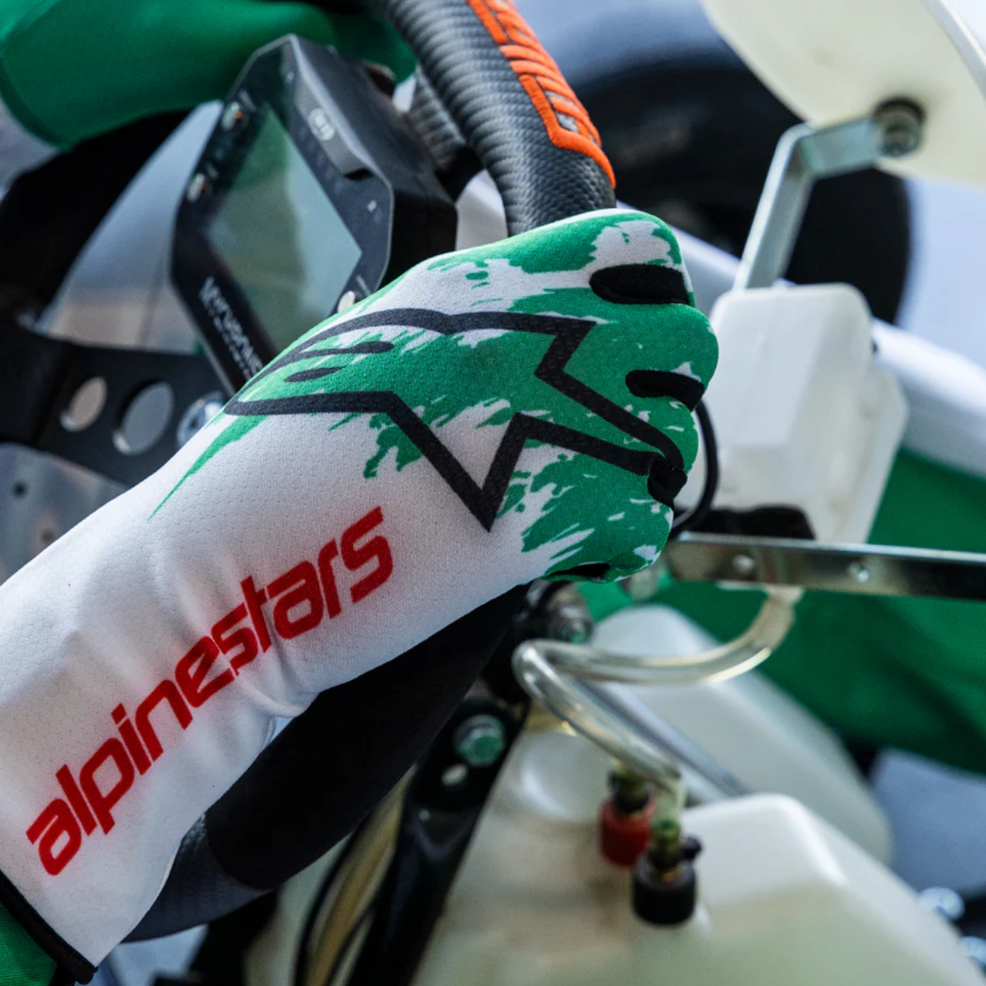 The white, green and red Alpinestars Tech-1 K v3 Karting Gloves in a karting lifestyle photograph.