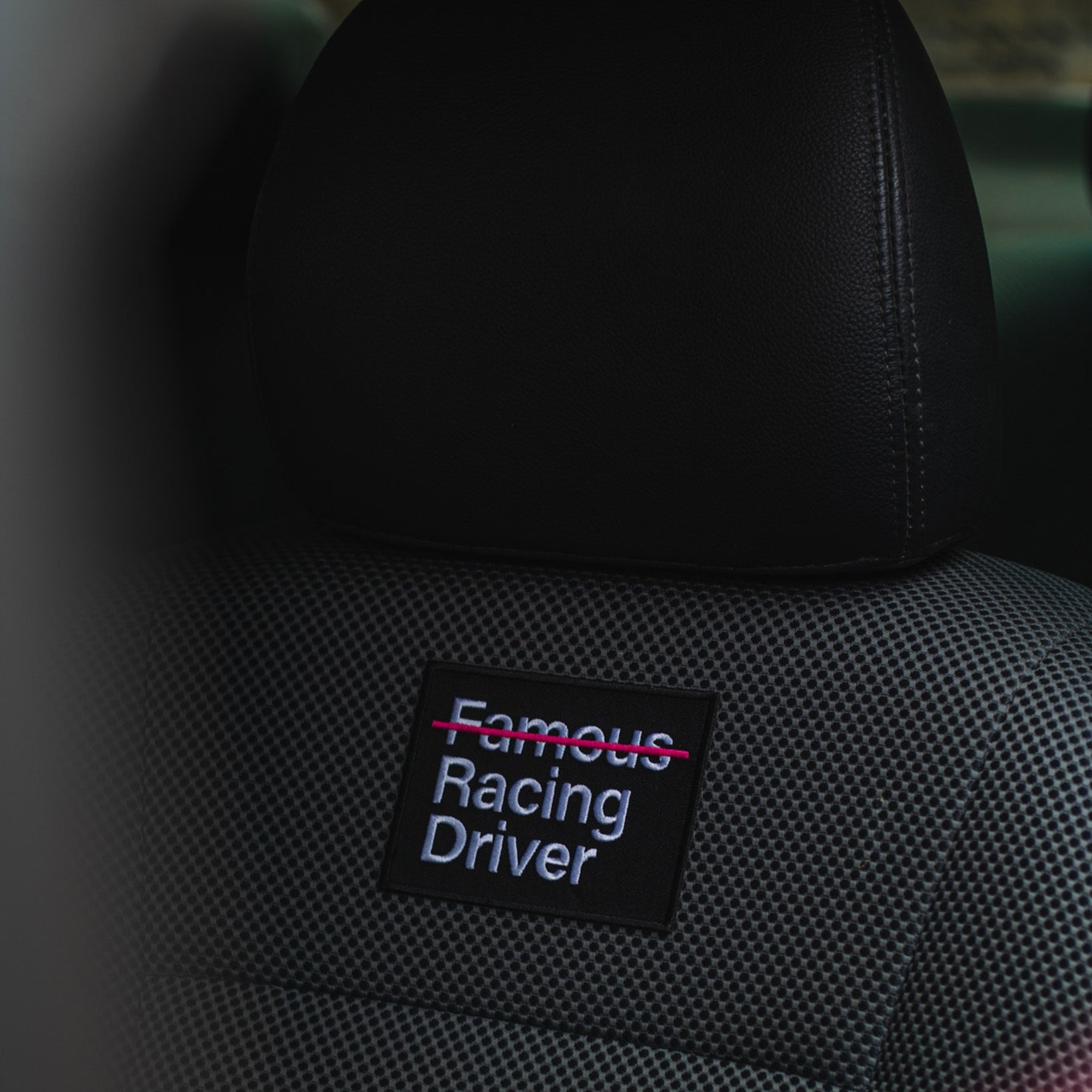 The NFRD (Not Famous Racing Driver) Patch from Not Famous Racing Apparel on a car seat.