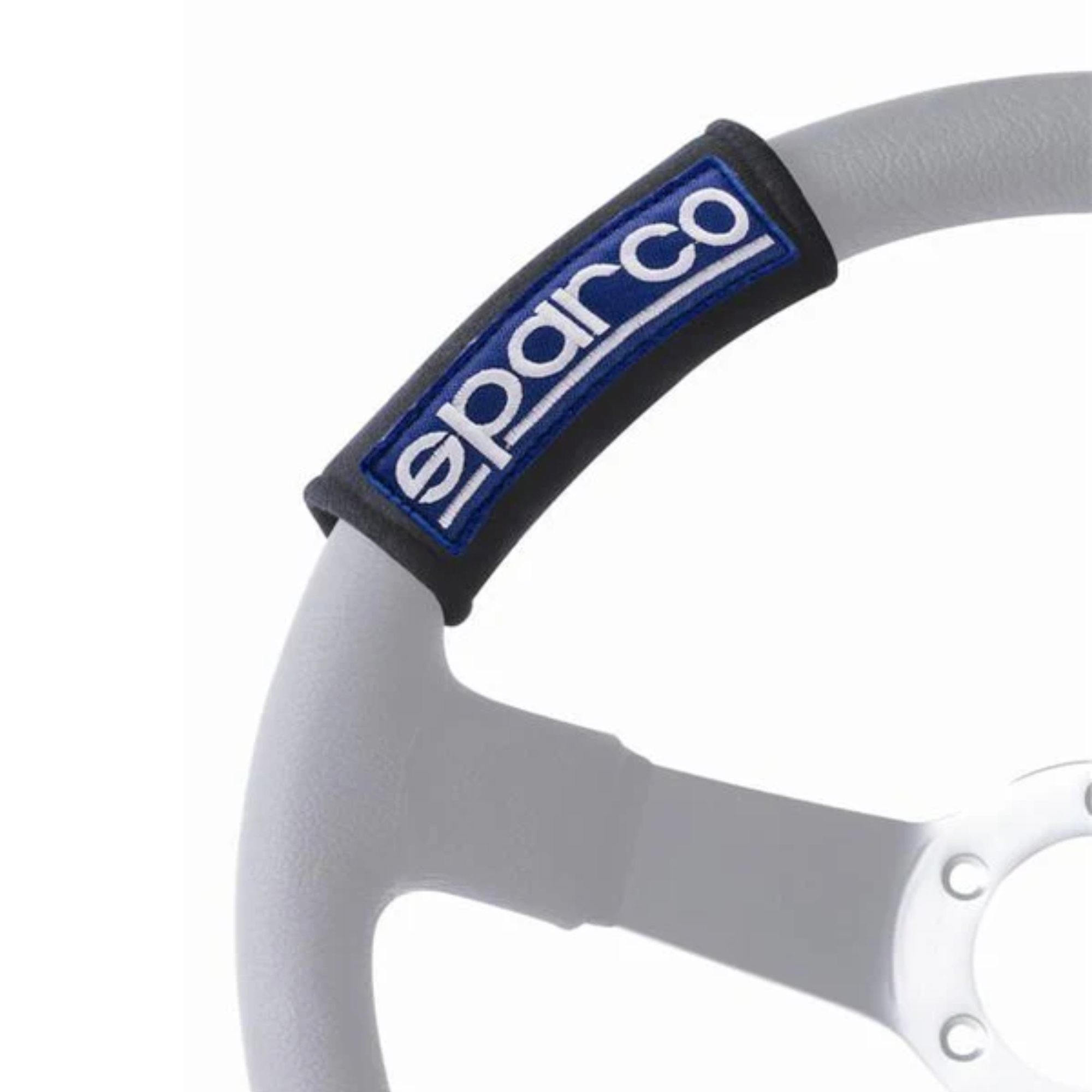 The black Sparco Mini Harness Belt Pad from Sparco on a steering wheel within a car. all-groups