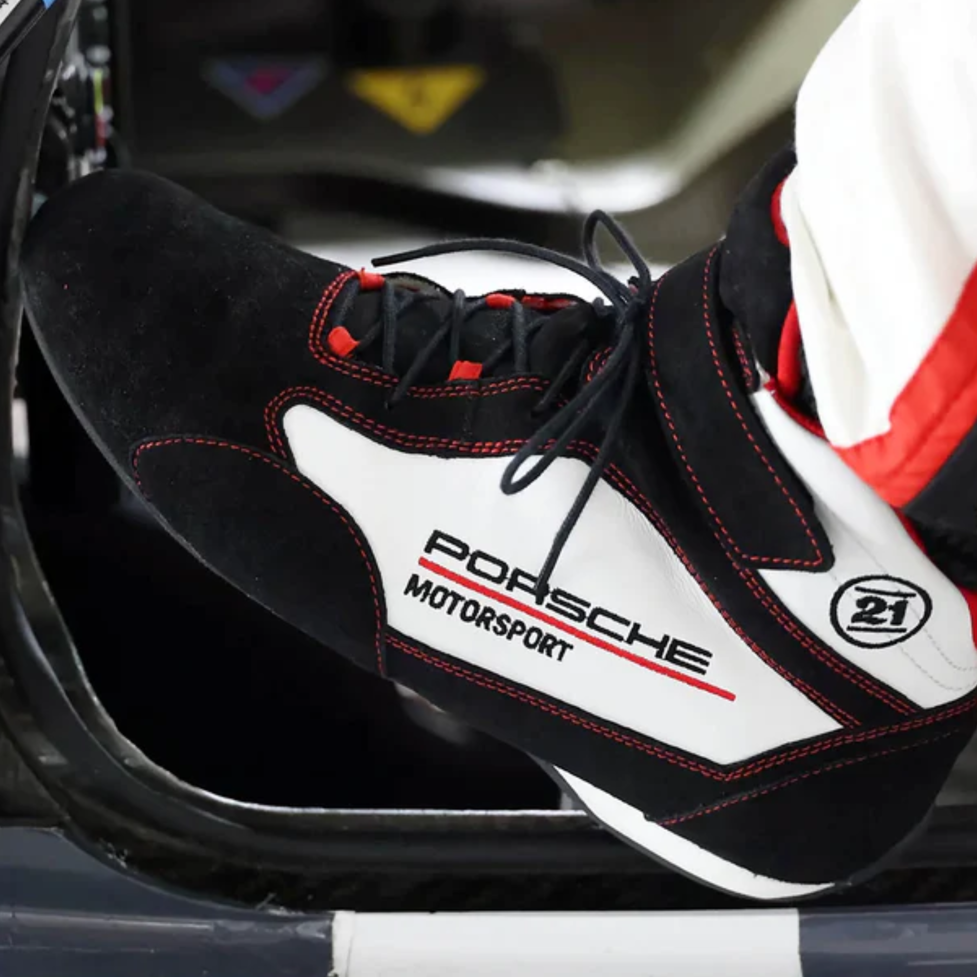 The black and white Stand-21 Porsche Motorsports Daytona3 Racing Shoes from Stand 21 in a driving lifestyle image.