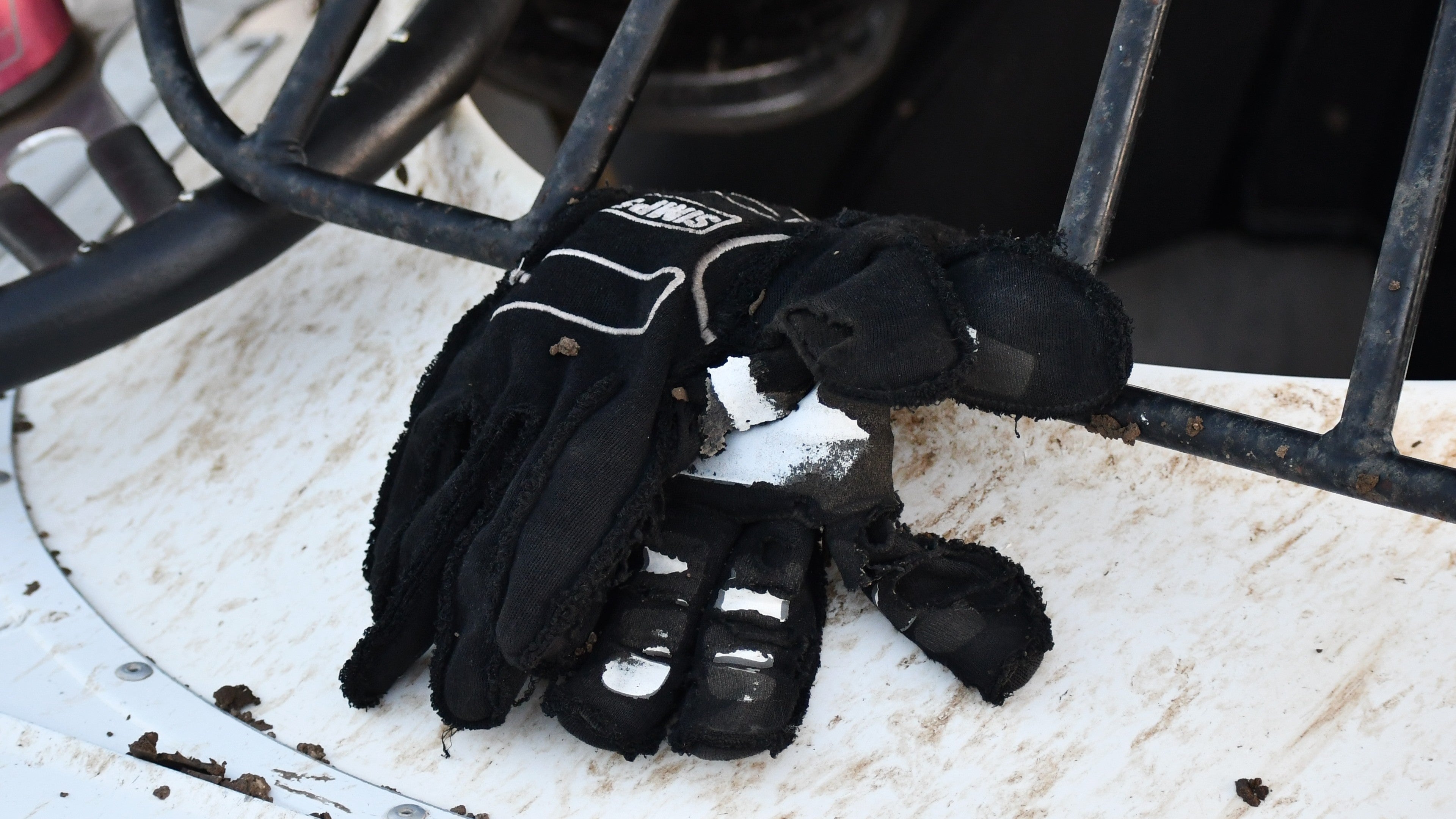 A pair of black and white Simpson racing gloves on a dirt racing car at the Watsonville Speedway.